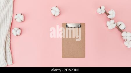 Flaches Lay von Zwischenablage, Handtuch und Baumwollblumen mit Kopierplatz auf einer rosa Oberfläche Stockfoto