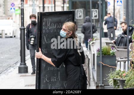 Schöne blonde Haare Kellnerin mit einer Maske Schließung Bar, Café oder Restaurant wegen neuer Quarantäne-Einschränkungen, während Coronavirus oder Covid Ausbruch Stockfoto