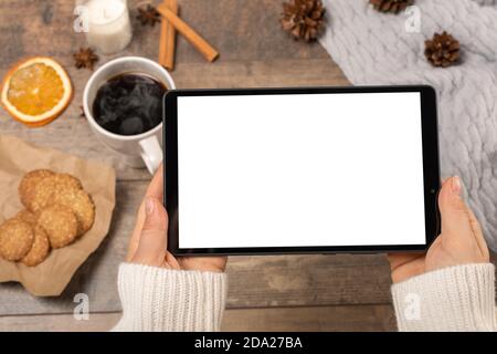 Mockup-Tablett. Frau zeigt leere weiße Bildschirm der digitalen Tablette. Tablette in weiblichen Händen. Frau hält eine Tablette mit einem weißen Bildschirm an einem Tisch in einem Café Stockfoto