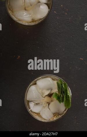 Brandy oder heller Rum mit Eis auf dunklem Hintergrund, Draufsicht Stockfoto