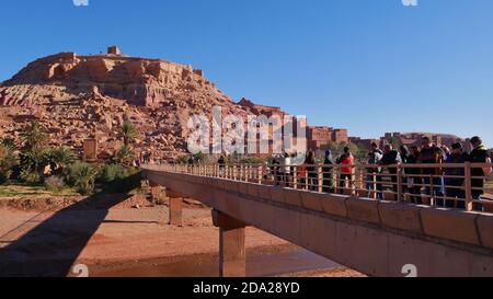 AIT Benhaddou, Marokko - 01/02/2020: Touristen überqueren eine Brücke auf dem Weg zum Eingang des beliebten historischen maurischen Ksar und UNESCO-Weltkulturerbe. Stockfoto