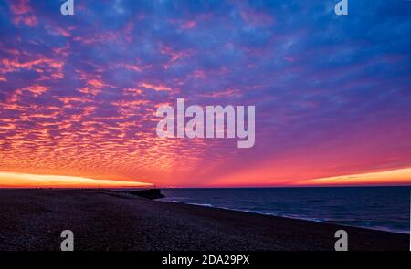 Dramatische rote Morgendämmerung Makrelen Himmel über dem Strand von Hastings In Ost-Sussex Süd-Ost-England Stockfoto