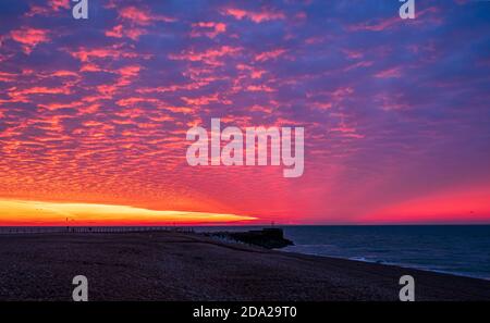 Dramatische rote Morgendämmerung Makrelen Himmel über dem Strand von Hastings In Ost-Sussex Süd-Ost-England Stockfoto