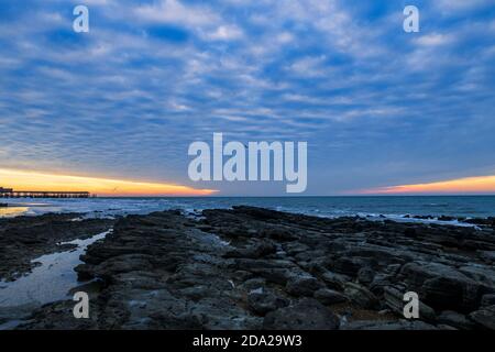 Dramatischer Makrelenhimmel im Morgengrauen über dem Hastings Pier in East Sussex südostengland Stockfoto