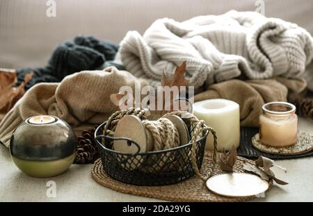 Herbstkomposition von Wohndekor Details, Kerzen, Seil und warme Kleidung auf dem Hintergrund. Komfort zu Hause, herbstliche Atmosphäre Stockfoto