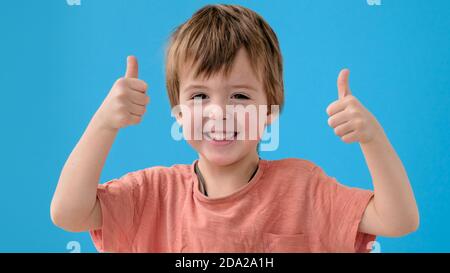 Lustiger Junge lächelt und zeigt Daumen-up posiert für Kamera Stockfoto