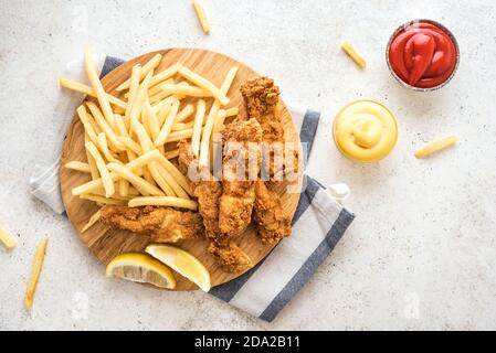 Fisch und Pommes. Frittiertes Fischfilet und mit pommes auf weißem Hintergrund mit Saucen. Traditionelles britisches Street Food, Draufsicht, Kopierraum. Stockfoto