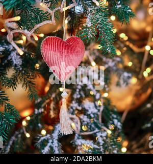 Christbaumzweig mit rotem Herz, Nahaufnahme. Silvester Liebe Ornament für festliche Dekor Stockfoto