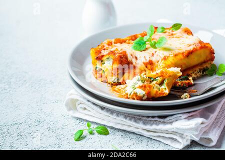 Stück Ricotta und Spinat Cannelloni auf grauem Teller. Italienisches Speisekonzept. Stockfoto
