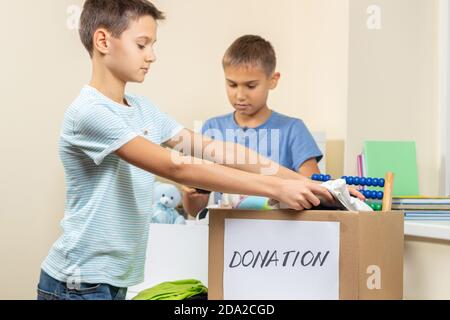 Kinder Freiwillige Sortieren Spielzeug, Kleidung, Bücher, Spenden Waren in Spenden Wohltätigkeitskisten im Haus Stockfoto