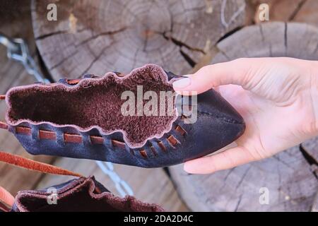 Ein schlichter schwarzer Stiefel aus rauem Leder. Schuhe in der Hand aus primitivem Material. Stockfoto