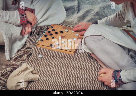 Spieler im Brettspiel im Vintage-Stil - tafl, hnefatafl. Zwei Personen spielen Tavlei, Nahaufnahme. Stockfoto