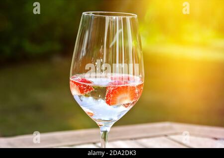 Ein Glas frischen Sekt mit Erdbeeren im Garten An einem sonnigen Tag Stockfoto