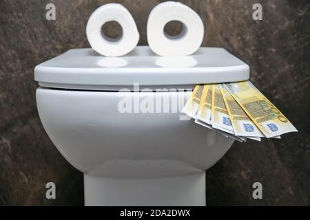 Lustige Toilettenschüssel mit Augen in Form von Toilette Papier, das Geld in Euro isst Stockfoto