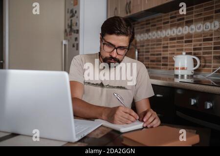 Konzentrierter Millennial Hipster Kerl trägt Brille, hören Lieblingsmusik während der Planung Arbeitstag. Fokussierte junge biracial Geschäftsmann beobachten e Stockfoto