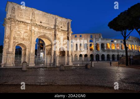 Bogen von Konstantin und Kolosseum bei Nacht in Rom, Italien. Alte Wahrzeichen der Stadt von Piazza del Arco di Costantino Platz. Stockfoto