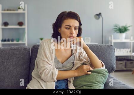 Junge Frau frustriert berühren Kinn während Online-Meeting Stockfoto