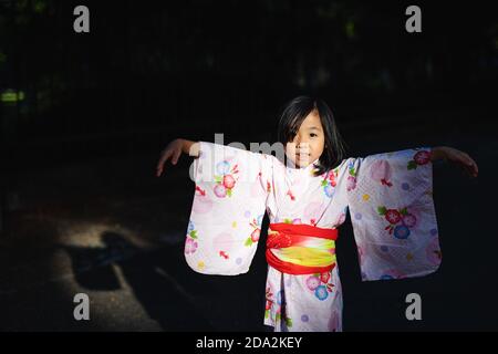 Porträt eines kleinen japanischen Mädchen trägt Kimono im Freien in der Stadt, Blick auf die Kamera. Stockfoto