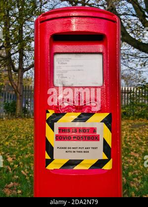 Eine rote UK-Postbox mit einem Schild, das darauf hinweist, dass die Box nicht für den Versand von COVID-Testkits verwendet werden sollte. Stockfoto
