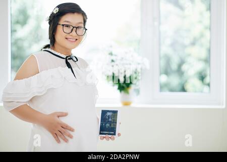 Schwangere Frau zeigt Ultraschallbild Stockfoto