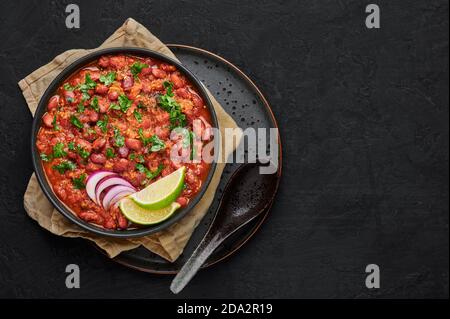 Rajma Masala Curry in schwarzer Schale auf dunkler Schieferplatte. Red Niere Bean Dal ist indische Küche vegetarisches Gericht. Asiatische Küche, Essen. Draufsicht. Kopieren Sie den SPAC Stockfoto