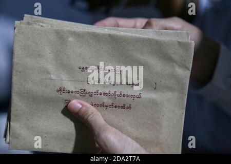 Während der Auszählung der Stimmen im Militärwahllokal hält ein Wahlbeamter Stimmzettel in ihren Briefumschlägen.Wahllokale in ganz Myanmar sind dabei, die Stimmen zu zählen, nachdem die Frist für die Wähler, ihre Stimme abzugeben, auf dem Myanmar 2020 General zu Ende geht Wahltag. Stockfoto