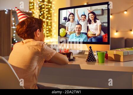 Geburtstagskind sitzt in der Nähe Monitor und Annahme Glückwünsche online von Verwandte oder Freunde Stockfoto