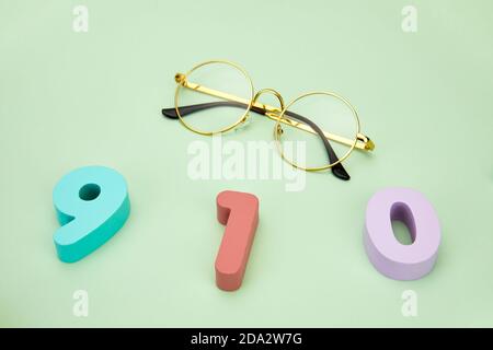Draufsicht auf 910 Zahlen mit Brillen auf einer Leuchte Grüne Oberfläche Stockfoto