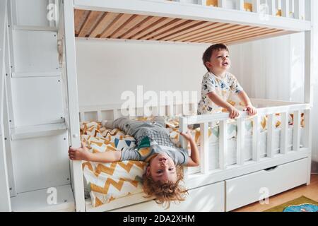 Zwei kleine Jungen ruhen sich aus und haben Spaß drinnen im Schlafzimmer zusammen Stockfoto