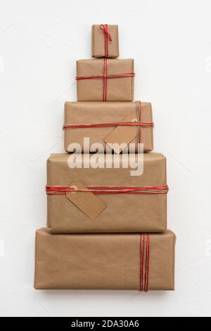 Weihnachtsgeschenkschachteln in Bastelpapier verpackt bilden ein Weihnachten Baumfigur auf weißem Hintergrund Stockfoto