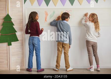 Rückansicht auf multi-ethnische Gruppe von Kindern Zeichnung an Wänden, während genießen Kunst-Klasse in der Schule, kopieren Raum Stockfoto