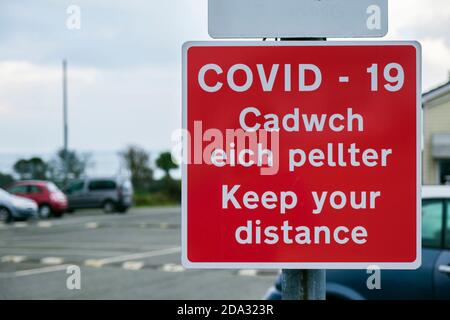 Coronavirus Pandemie Covid-19 zweisprachige Schilderwarnung Halten Sie Abstand in Englisch und Cadwch eich Pellter in Walisisch. Anglesey North Wales Großbritannien Stockfoto