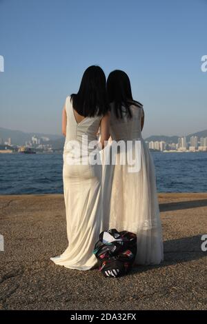 Zwei glückliche Bräute von hinten gesehen, die Fotos machen Sai Wan Cargo Pier (auch Instagram Pier genannt) In Hongkong Stockfoto