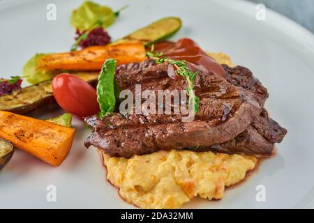 Gegrilltes Steak auf Kartoffelpüree mit gegrilltem Gemüse. Stockfoto