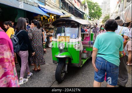 Tuk Tuk Taxi fährt auf einem belebten Straßenmarkt entlang Silom 20 Gasse Stockfoto