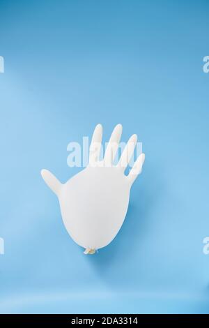 Ein isolierter aufgeblasene Latexhandschuh auf blauem Hintergrund. Covid-19 Personenschutz. Latex Handschuh Ballon. Stockfoto