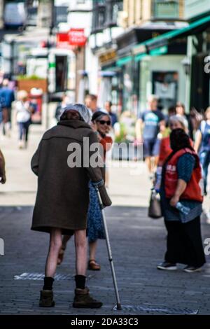 WINCHESTER, VEREINIGTES KÖNIGREICH - Jul 16, 2020: Armer alter Mann nur in langer Mantel gekleidet, der mit Gehstock die Straße entlang läuft, isoliert von der Gesellschaft p Stockfoto