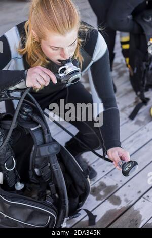 Scuba Diver Kitting und Überprüfung ihrer Ausrüstung, Test Regler und Manometer Stockfoto