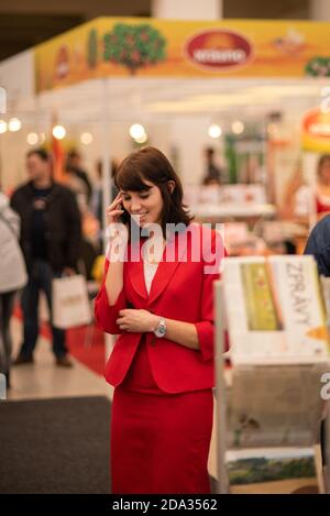 Frau, die am Telefon spricht und an einer Veranstaltung im Messezentrum in Brünn teilnimmt. Messe Brünn. Tschechische Republik Stockfoto