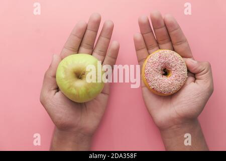 Halten Apfelfrüchte und Donut, wählen Sie gesunde Ernährung Konzept. Stockfoto