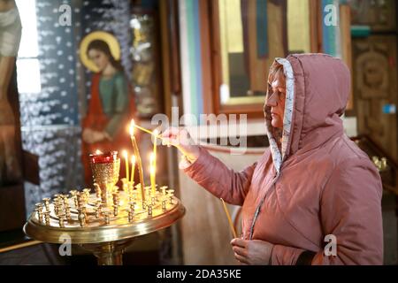 Die ältere Frau stellt die Kerze für die Gesundheit in der russisch-orthodoxen Kirche Stockfoto