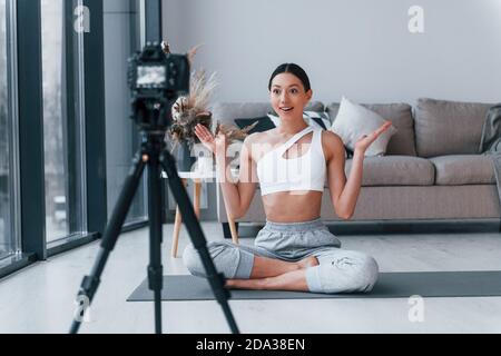 Blogger junge Frau mit schlanken Körperform in Sportswear tun Yoga zuhause Stockfoto