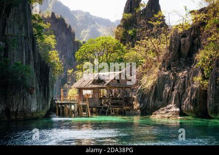 Blick auf Holzhütte in ruhigem Meer gegen Felsformation, Philippinen Stockfoto