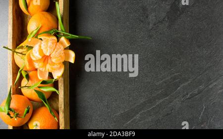 Frische Mandarinen in Holzschale auf dunklem Tischhintergrund oben Anzeigen Stockfoto