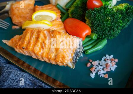 Gegrilltes Lachssteak mit Kräutern, Tomaten, Rosenkohl und Blumenkohl werden zum Abendessen serviert. Diätgericht der mediterranen Ernährung Stockfoto