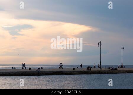 Triest, Italien. Molo Audace Leute, die in der Dämmerung auf dem Pier spazieren Stockfoto