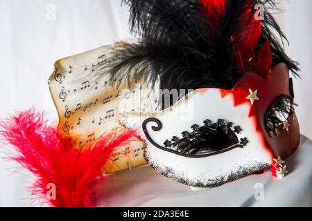 Nahaufnahme von Maske und Federn auf einem Tisch bei einem Maskenball-Event. Stockfoto