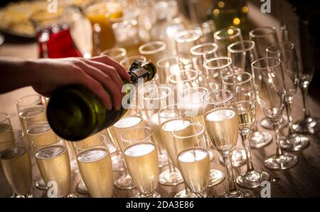 Champagner auf einer Party in Sektflöten gießen. Stockfoto