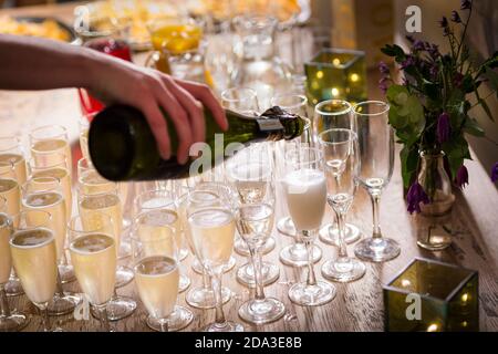 Champagner auf einer Party in Sektflöten gießen. Stockfoto