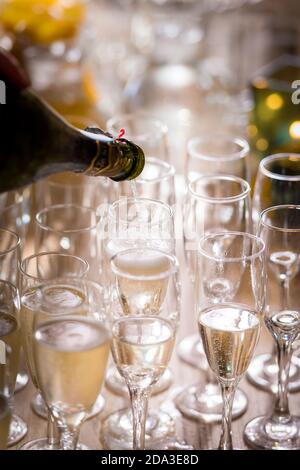 Champagner auf einer Party in Sektflöten gießen. Stockfoto